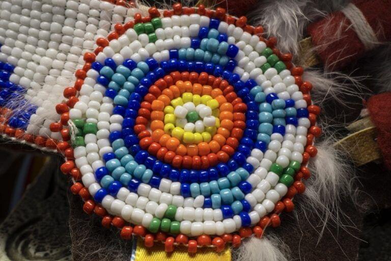 Close-up of a colorful beaded medallion with concentric circular patterns, representing Indigenous Minnesota tribal partners.
