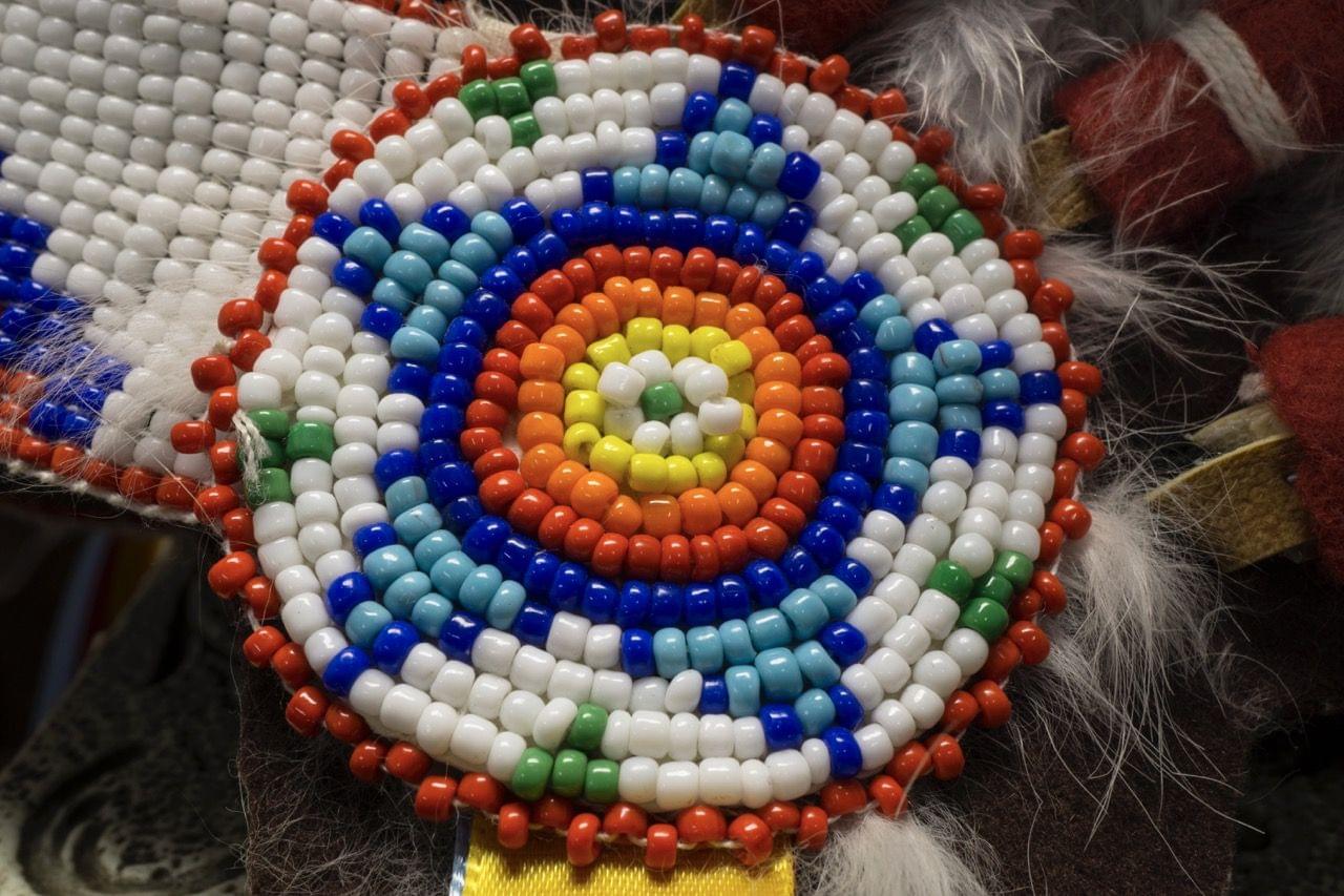 Close-up of a colorful beaded medallion with concentric circular patterns, representing Indigenous Minnesota tribal partners.