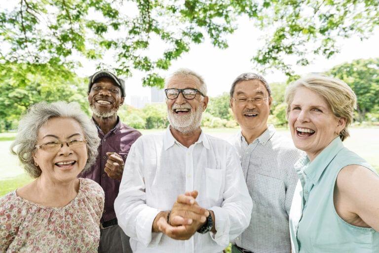 Diverse older people outside smiling at the camera