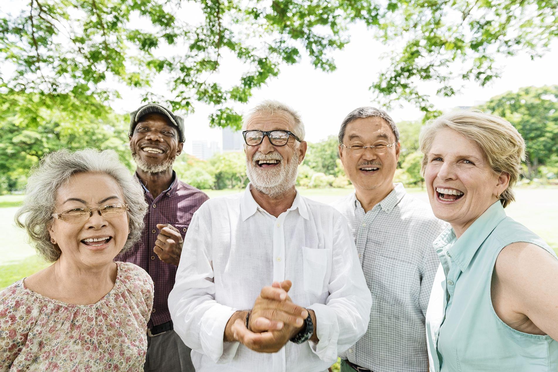 Diverse older people outside smiling at the camera