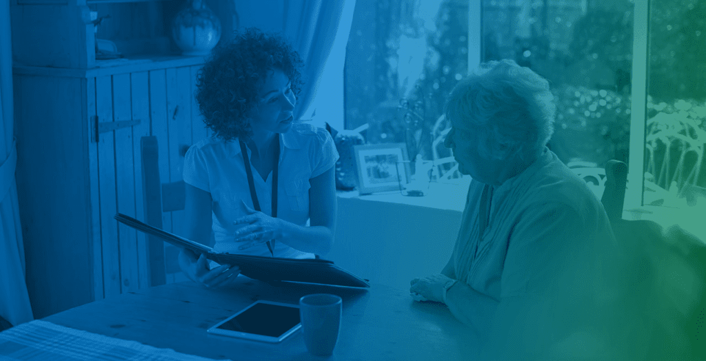 Two people in a caregiving discussion beside a table with a tablet and smartphone.