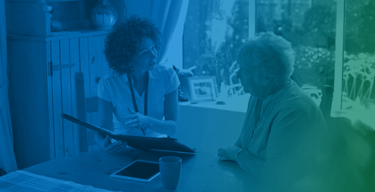 Two people in a caregiving discussion beside a table with a tablet and smartphone.