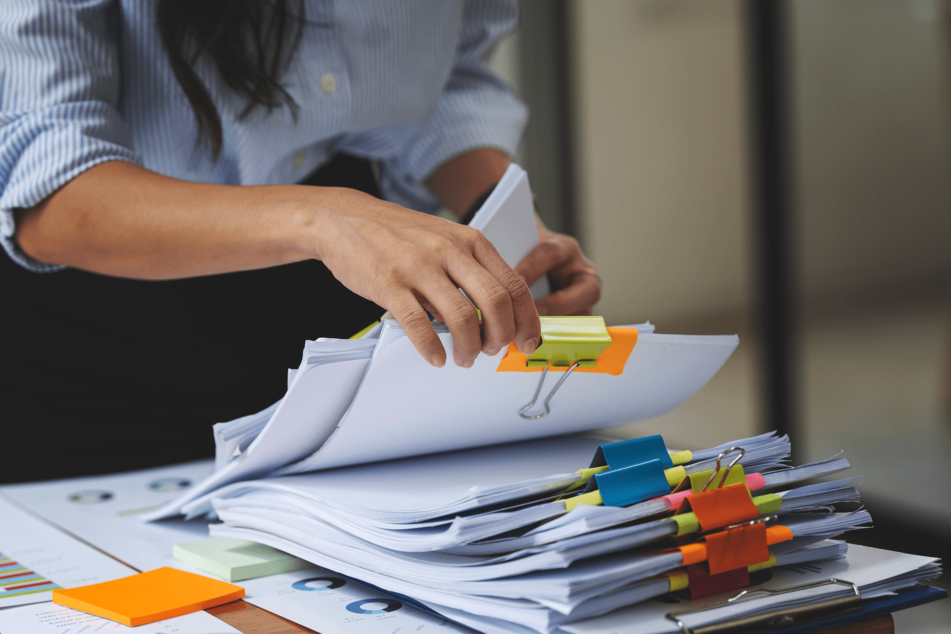 Person organizing a long distance stack of documents with colorful sticky tabs.