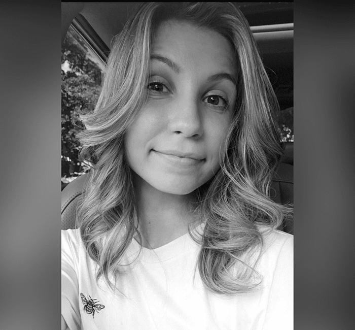A black and white portrait of a smiling woman with wavy hair.