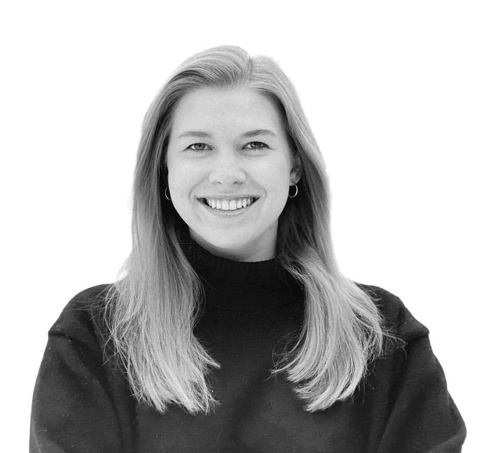 A black and white portrait of a smiling woman with long hair, wearing a high-neck sweater.