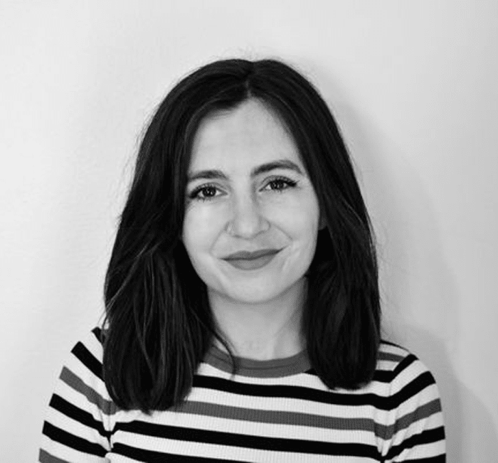 Black and white photo of a smiling woman with shoulder-length hair wearing a striped top.