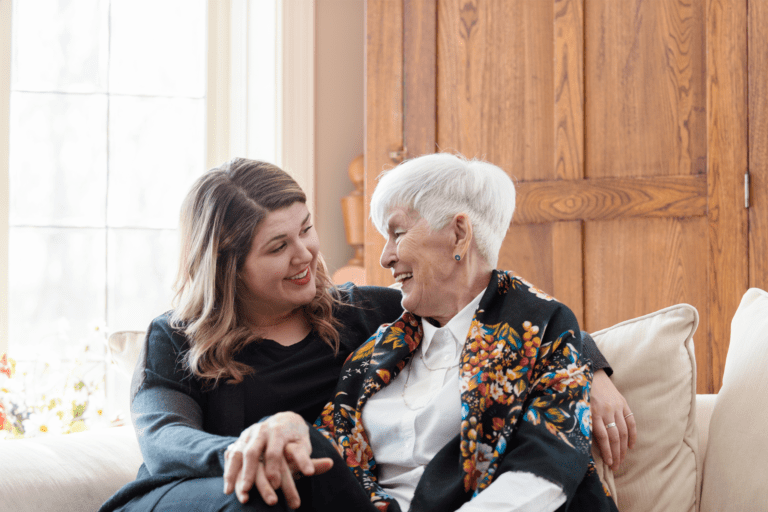 Two women of different generations sharing a joyful moment together on a couch, illustrating the essence captured in Trualta's press releases.