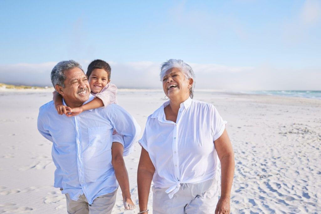 grandparents walking on the beach with their grandson