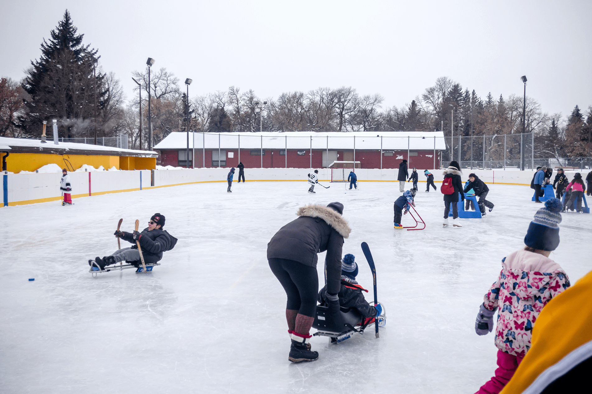 People engaging in various ice sports activities on an outdoor rink in winter, covered by Trualta press releases.