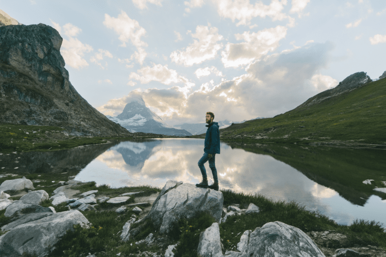 Man standing by a mountain lake with a Trualta press release reflected in the waters, showcasing the Matterhorn in the background.
