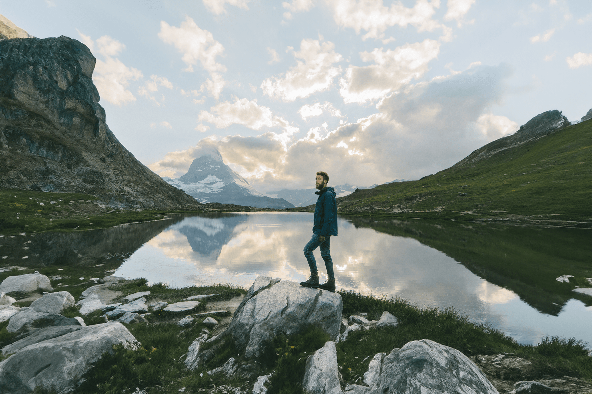 Man standing by a mountain lake with a Trualta press release reflected in the waters, showcasing the Matterhorn in the background.