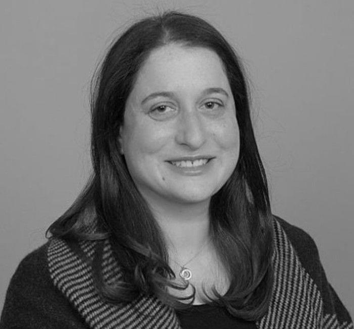 Black and white portrait of a smiling woman with medium-length hair and a striped garment.