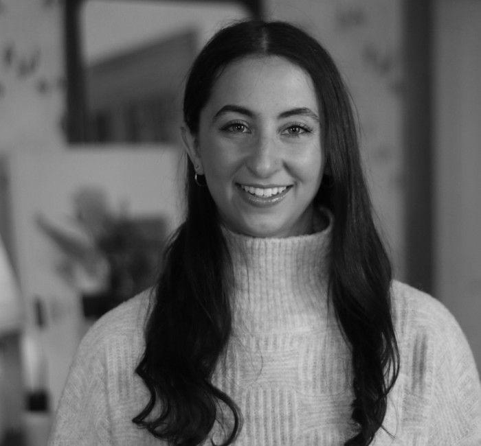A black and white portrait of a smiling woman with long hair, wearing a turtleneck sweater.