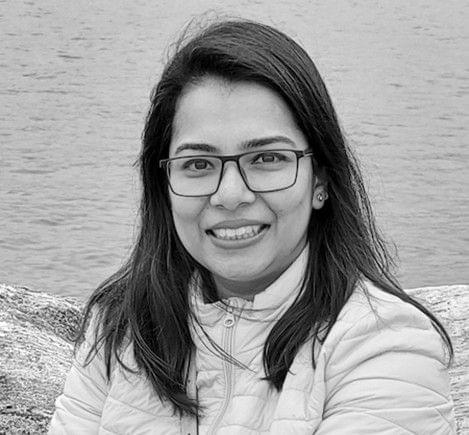 Woman with glasses smiling outdoors.