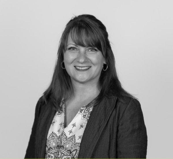 A black and white portrait of a smiling woman with medium-length hair.
